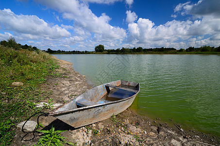 河岸上的Rusty船镜子木头血管植物绿水环境支撑地平线池塘蓝色图片