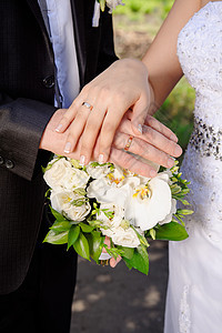 新娘和新郎手牵手 在婚礼花束上戴戒指钻石蜜月男性庆典夫妻接待指甲仪式生活订婚图片