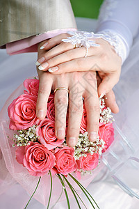 新娘和新郎手握着戒指 在新娘的花束上图片