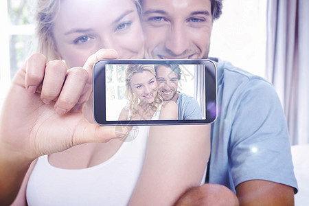 手持智能手机显示的复合图象男性家庭金发微笑枕头房子头发电话技术自拍图片