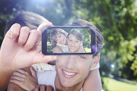 手持智能手机显示的复合图象长椅太阳女朋友阳光男性快乐展示女性屏幕女士图片