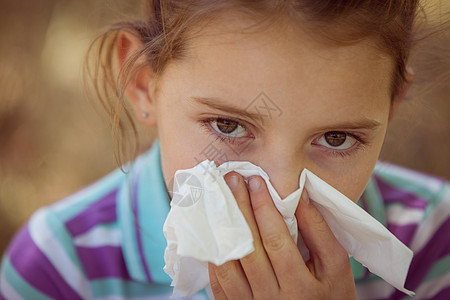 可爱的小女孩吹她的鼻子 在公园阳光男性农村花粉草地绿色流感鼻涕晴天感染图片