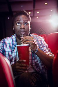 文艺演出年轻人在看电影和喝苏打水时间活动闲暇男性椅子演出震惊黑色电影红色背景