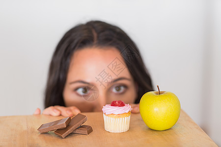 漂亮的黑发美女偷看餐桌上的食物图片