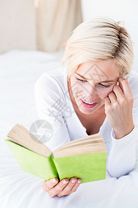 躺在床上微笑着的金发女人 在看书女士快乐女性知识分子头发公寓棉被闲暇小说羽绒被图片
