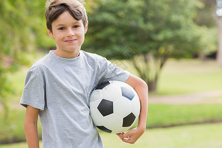在公园里拿着足球球的笑男孩阳光棕色男性闲暇绿地草地快乐晴天男生绿色图片