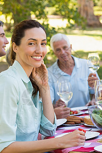 美丽的黑发美女在野餐时对着镜头微笑男人头发互动餐桌晴天活动家庭男性棕色农村图片