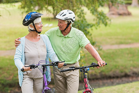 骑自行车的老年快乐情侣微笑男性农村女性闲暇阳光环境感情娱乐头盔图片