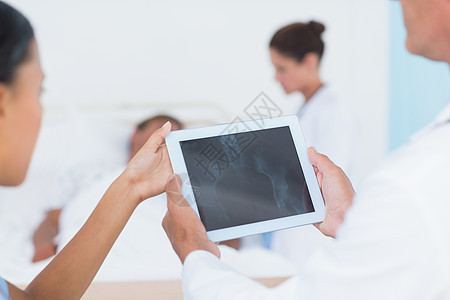 医生与同事和病人在后面使用数字平板电脑药片工作滚动说谎职业病房女士医院疾病保健图片