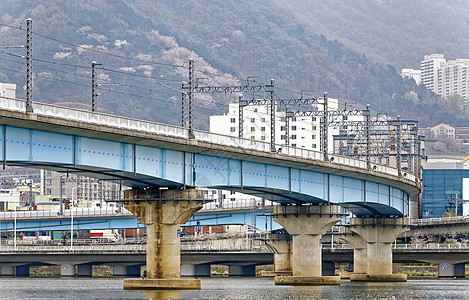 公共汽车横跨河流和城市背景的火车桥图片