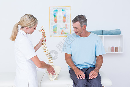 医生向病人展示解剖脊椎女性压力按摩师药品办公室人骨解剖学痛苦互动治疗图片