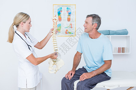 医生向病人展示解剖脊椎女士颈椎讨论疝气治疗痛苦疾病压力女性按摩师图片