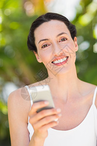 穿着白衣服看手机的女人眼睛拨号微笑快乐电话女性头发棕色女士呼唤背景图片