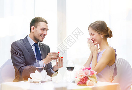 男人向在餐厅的女朋友求婚的男人幸福首饰订婚纪念日戒指周年盒子婚姻花朵展示图片