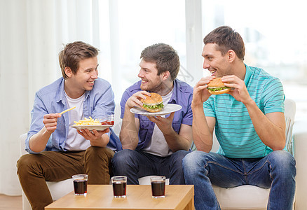 在家带苏打和汉堡的笑着朋友派对男性娱乐食物眼镜垃圾队友友谊房间沙发图片