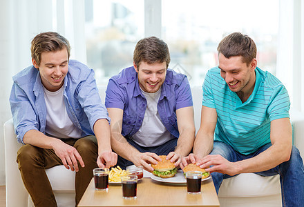 在家带苏打和汉堡的笑着朋友伙计们学士土豆青少年小吃幸福食物友谊派对眼镜图片