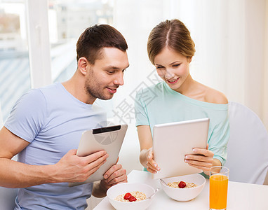 微笑的情侣与平板电脑Pc阅读新闻谷物果汁女朋友技术成人家庭面包妻子早餐男人图片