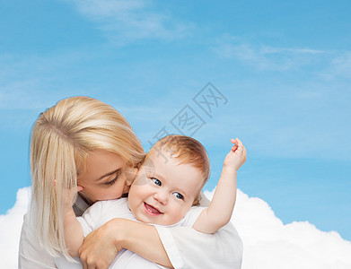 快乐的母亲亲吻微笑的婴儿女孩妈妈儿子蓝色孩子女士拥抱生活天空童年图片