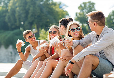 一群笑着的朋友坐在市广场上假期情侣食物垃圾太阳镜友谊团体游客女性幸福图片