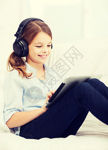 家里有平板电脑和耳机的女孩娱乐学生互联网青春期立体声歌曲闲暇音乐播放器技术收音机图片
