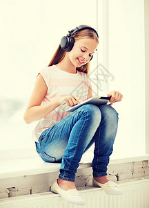 家里有平板电脑和耳机的女孩互联网技术青少年药片音乐播放器孩子立体声歌曲播客娱乐图片