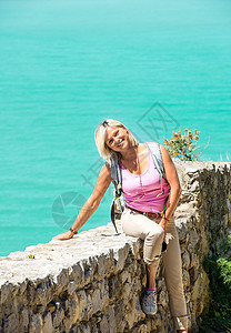 坐在石墙上的年轻笑笑的金发金发女孩图片