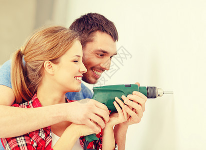 在家里墙上闪着微笑的对夫妇钻洞钻头木匠装修家庭建筑工作安全建设者维修改造图片