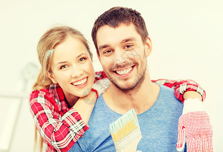 一对微笑的夫妇 涂满油漆和油漆刷梯子团队幸福女士拥抱装修公寓男性男人手套图片