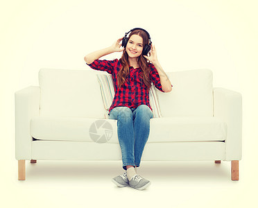 坐在沙发上戴耳机的女童收音机享受热情喜悦打碟机女孩乐趣女性说谎长椅图片