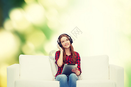 用耳机和平板电脑坐在沙发上的女孩微笑生态打碟机歌曲女士娱乐音乐音乐播放器收音机幸福图片