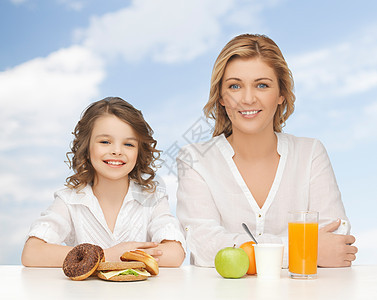 快乐的母亲和女儿在吃早餐青春期青少年孩子女孩包子食物甜甜圈父母微笑甜点图片