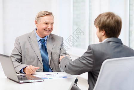 年长男子和年轻男子在办公室握手笔记本老板合伙工人欢呼伙伴人士交易代理人员工图片