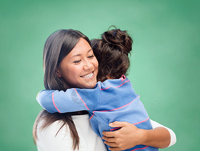 快乐的女子和小女孩 拥抱在学校图片