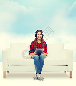 用耳机和平板电脑坐在沙发上的女孩技术打碟机蓝色热情药片互联网播客青少年立体声女士图片