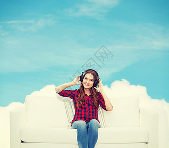 坐在沙发上戴耳机的女童微笑天空立体声女孩青年歌曲闲暇音乐娱乐享受图片