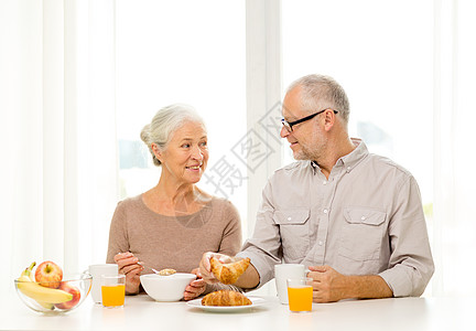 喝果汁的情侣在家吃早餐的年长快乐情侣玉米片丈夫房间家庭眼镜夫妻幸福果汁女士祖母背景