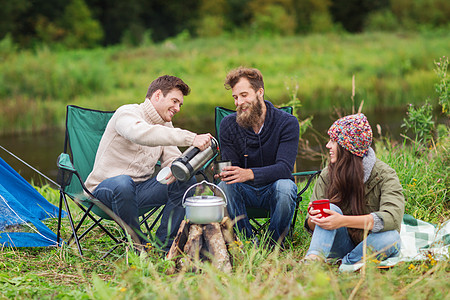 一群微笑的游客在露营中做饭营火旅行椅子森林友谊女朋友家庭探险家烹饪男朋友图片