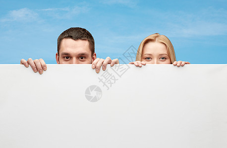 躲在大白白空白板后面的幸福情侣夫妻广告牌笔记木板天空蓝色拉丁广告女士面孔背景图片
