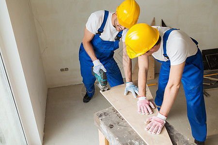 室内装配工具的建筑工组群男性木匠装修连体衣机器安全帽工人男人承包商桌子图片