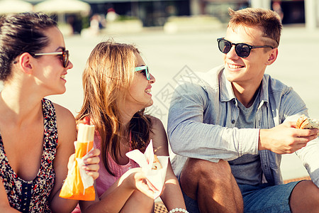 一群笑着的朋友坐在市广场上会议色调情侣潮人乐趣友谊男人青少年热狗零食图片