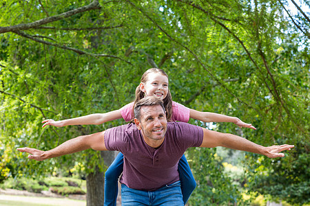 父亲和女儿在公园玩得开心微笑团结童年肩膀晴天绿地男性女性阳光家庭图片