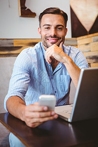 利用笔记本电脑微笑的商务人士餐厅饮料双手手机咖啡馆商业咖啡屋男性顾客袖子图片