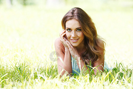 穿着蓝裙子的年轻女子躺在草地上幸福绿色成人微笑女孩公园女性金发蓝色图片