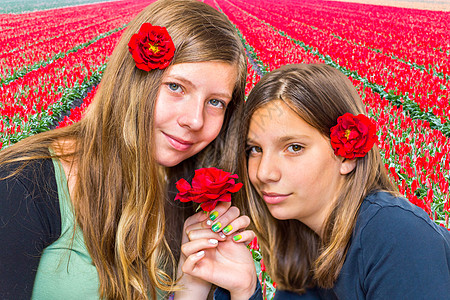 两个女孩在郁金香田前 带着红玫瑰图片