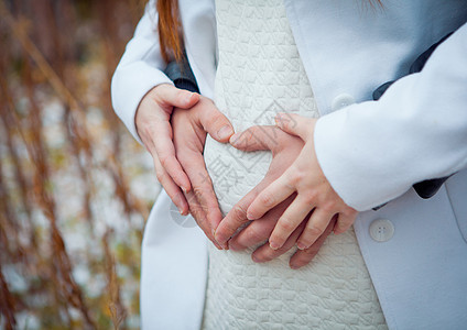 孕妇在婴儿潮中握着她双手的心脏部位 怀有手指符号的Belly怀孕 生育概念 爱婴淋浴女性产妇肚子女士腹部母性压痛孩子成人母亲图片