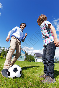 踢足球女孩父亲和儿子踢足球幸福女性男性牛仔裤财产住宅微笑房子足球游戏背景