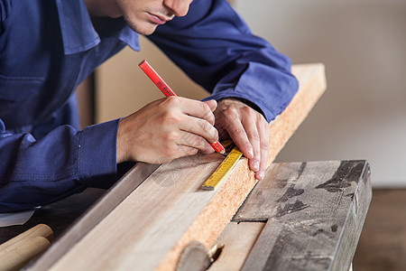 木工在一块木柴上作记号的木匠测量工作职业财产木材男性男人统治者工人作坊图片