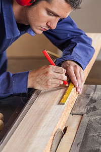 木工在一块木柴上作记号的木匠乐器工人职业红色木材铅笔木头测量围裙男人图片