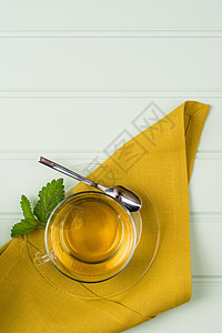 一杯杯子里有香草茶和美莉萨毛巾黄色玻璃绿色药品植物早餐健康草本饮料图片