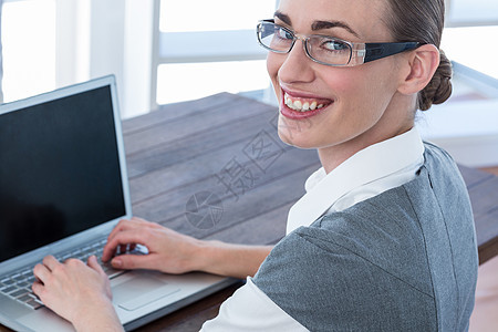 商业女商务人士看戴眼镜的照相机和使用笔记本电脑图片